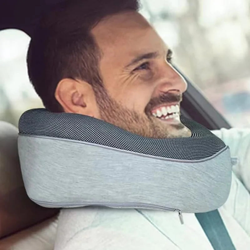 "Man wearing a gray and black mesh ergonomic neck pillow while seated in a vehicle.