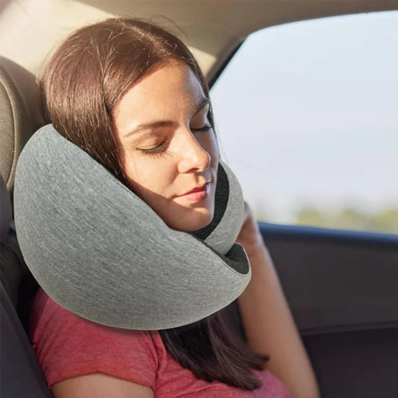 Woman sleeping comfortably in a car using an ergonomic gray travel neck pillow.