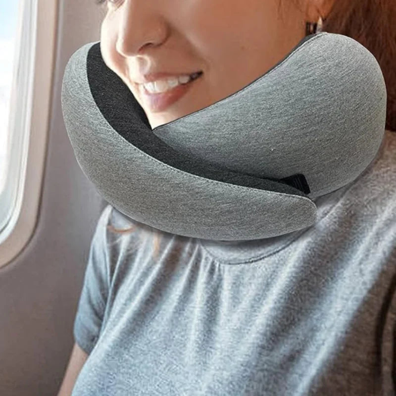 Woman using a gray ergonomic travel neck pillow on a flight.